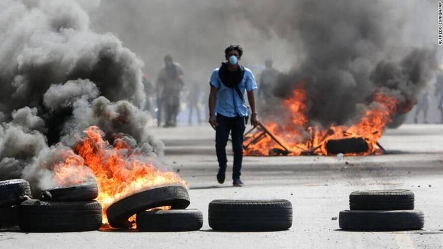 A Nicaraguan protester walks among burning barricades during political unrest in Managua this summer.