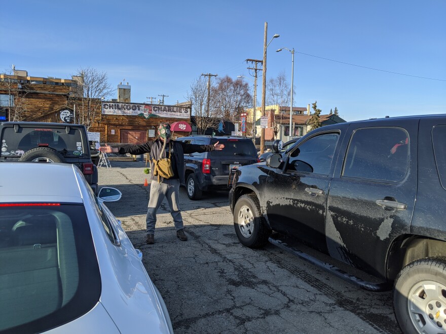 Greg Rowland, a local comic, helps direct traffic and uses his wingspan to ensure cars are parked six feet apart from each other in the parking lot of Chilkoot Charlie's in Anchorage on April 10, 2020. Rowland has been out of work for some time but is happy about how this new stand up comedy event has turned out. (Mayowa Aina/Alaska Public Media)