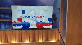 Decision 2026 graphic behind a podium microphone