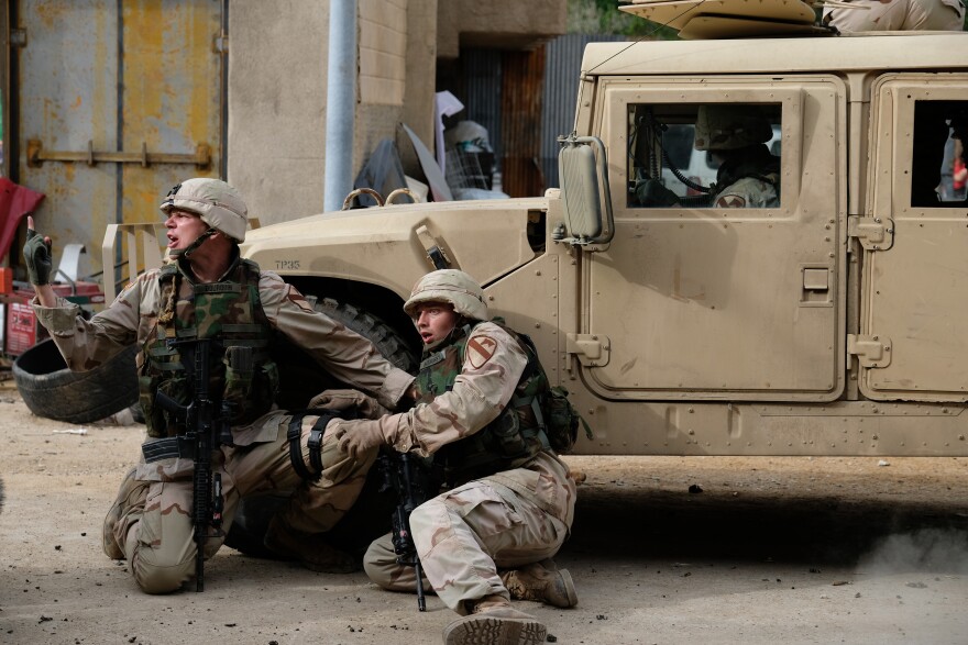 Actors Patrick Schwarzenegger (left) and Jon Beavers crouch in position on set of "The Long Road Home."