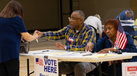 Saginaw Township poll workers Vincent McMillon and May Wathen help a voter prepare to cast her ballot in the Aug. 4, 2026 primary election.