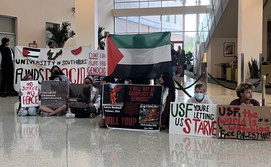 Students holding signs and flags in a lobby. 