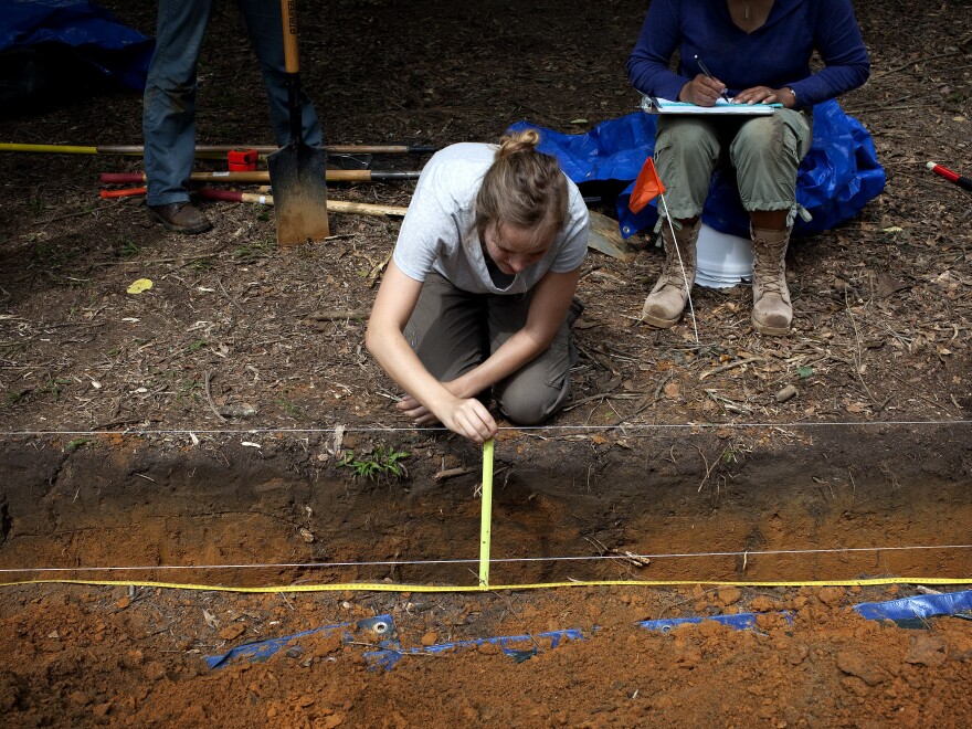 Meredith Tise, a graduate anthropology student at the University of South Florida, measures the depth of a trench dug at the site of the cemetery last May, as the university looks for signs of unmarked graves.