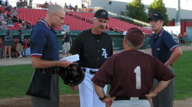 Bill Buckner, in black, speaks with umpires and the opposing manager before a 2011 Brockton Rox game. (Anthony Brooks/WBUR)