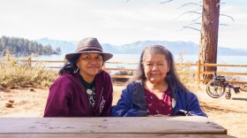 Two women sit at a picnic table in front of Lake Tahoe on the shores of Zephyr Cove.