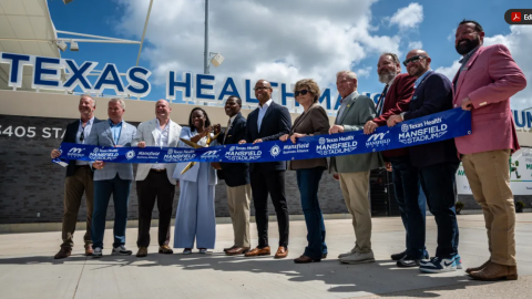 Community leaders and project developers pose with a ceremonial ribbon and scissors to commemorate the opening of Texas Health Mansfield Stadium July 1, 2026, in Mansfield.