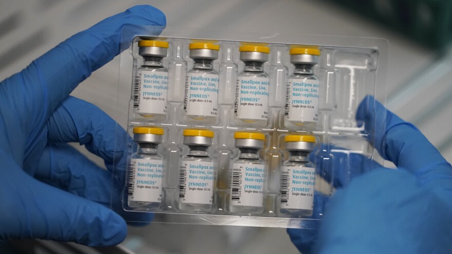 A doctor holds vials of the monkeypox vaccine over a table.