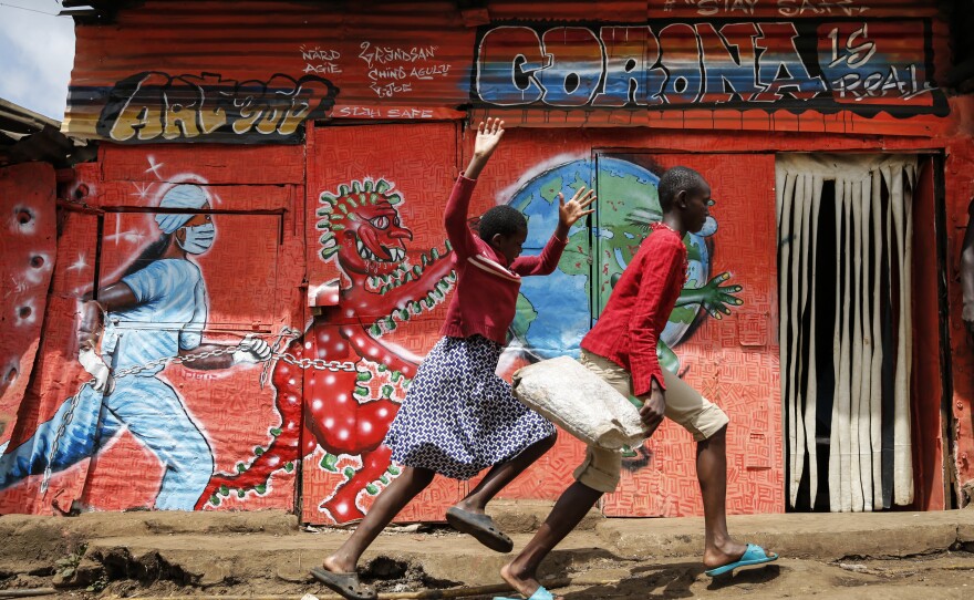 Children run down a street past an informational mural warning people about the dangers of the coronavirus in the Kibera settlement in Nairobi, Kenya, June 3.