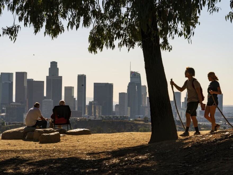 Albert Maghbouleh, far left, and Miles Santamour, 89, with Amigos de Jaibalito Foundation (ADJ) share lunch outdoors guarding social distancing, overlooking the skyline of Los Angeles Monday, Jan. 11. (AP Photo/Damian Dovarganes)