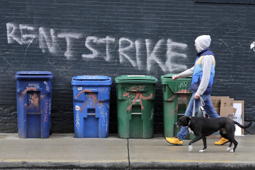 A pedestrian walks past graffiti that reads "Rent Strike" April 1, 2020, in Seattle's Capitol Hill neighborhood. 