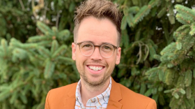 Smiling man with glasses in orange blazer outdoors