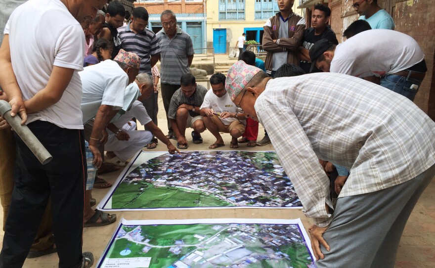 Residents of Panga, a town in Nepal hit hard by the 2015 earthquake, study a map of their area put together with drone images that Meier and his partners gathered.