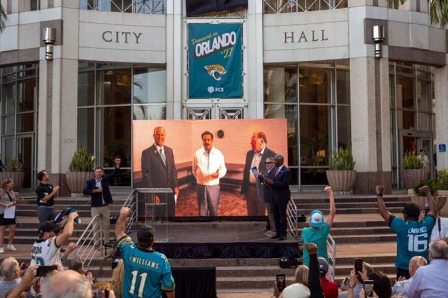 ans cheered in front of Orlando City Hall on Tuesday evening as Jacksonville Jaguars owner Shahid Khan, center, announced that Orlando’s Camping World Stadium would host his team during the 2027 NFL season.