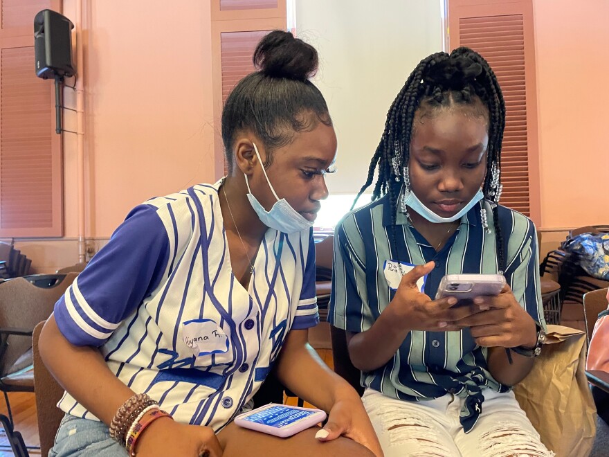 Kiyana Richards and Paris Vassell, both 15-year-old students from Dennis-Yarmouth Regional High School, write out their comments and compare notes before speaking to the mock select board.