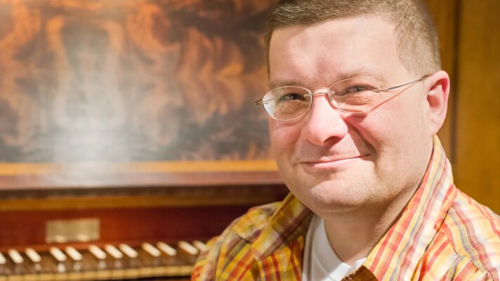 A man posed in front of an organ keyboard