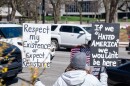 A protester holds two signs up to traffic on South Calhoun Street in downtown Fort Wayne on Saturday. Protesters stretched down both sides of the street, from the intersection of East Berry Street down past the Rousseau Center.