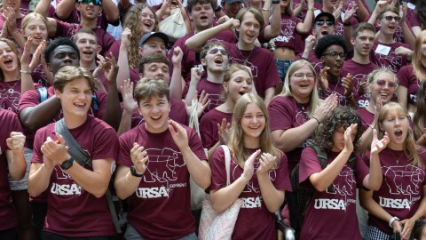 a group of students cheer in maroon URSA shirts