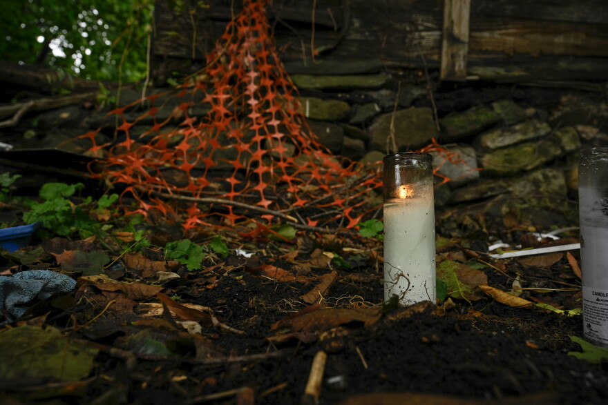 A candle burns in the backyard of an abandoned home where the remains of a child were found in Connecticut. Under a new state law adopted in 2024, the Department of Children and Families must release certain information about children who die or nearly die due to abuse or neglect.