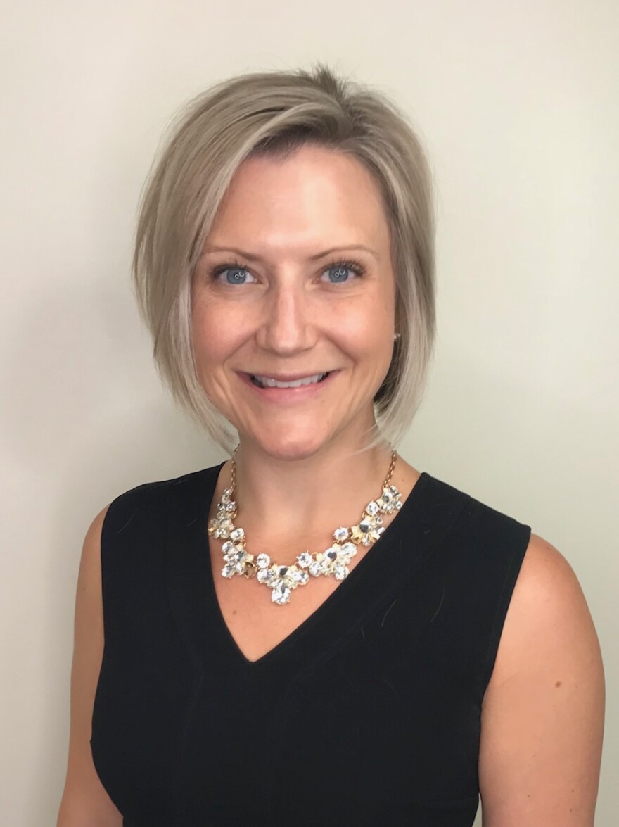 Dr. Kaylin Klie, a woman with short blonde hair, wearing a necklace and a sleeveless black shirt smiles in a photo