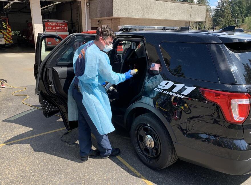 Jacob Czekanski of South King Fire and Rescue decontaminates a police cruiser at Station 61 in Auburn, Washington.