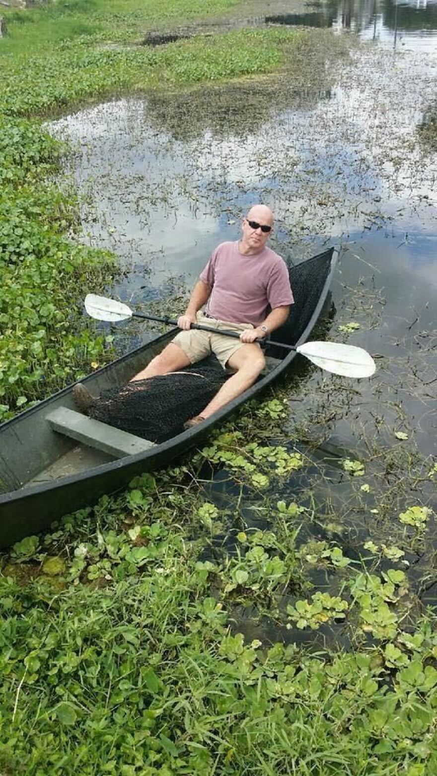 Man kayaking in swampy water  