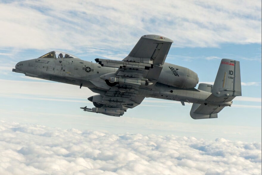 A picture of an A-10 Thunderbolt aircraft flying against a blue sky peppered in clouds 