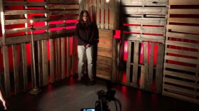 A student stands in front of a videocamera during a recording of her performance in the play
