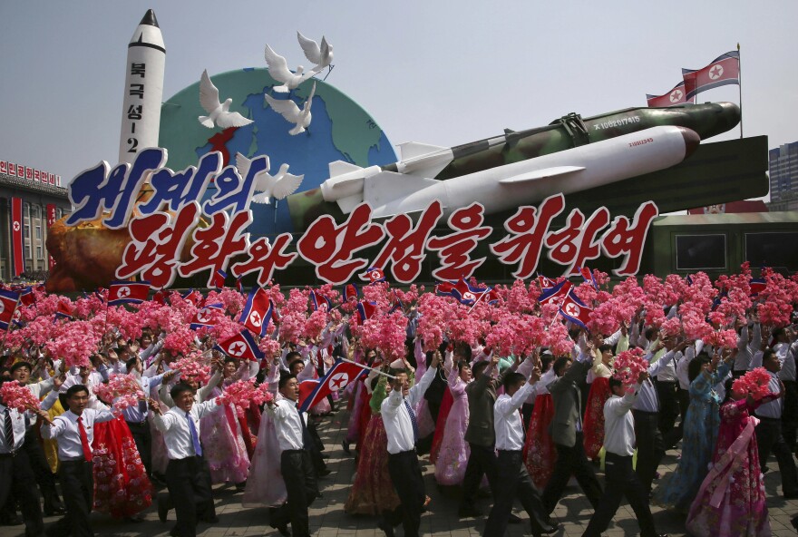 North Koreans wave as they march next to a float display of models of different missiles across Kim Il Sung Square in Pyongyang. The military parade celebrated the 105th birth anniversary of Kim Il Sung on April 15.