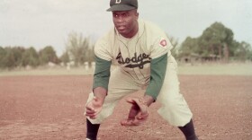 American professional baseball player Jackie Robinson (1919 - 1972) of the Brooklyn Dodgers, dressed in a road uniform, crouches by the base and prepares to catch a ball, 1951. Throughout the course of his baseball career Robinson played several positions on the infield as well as serving as outfielder. (Photo by Keystone/Getty Images)