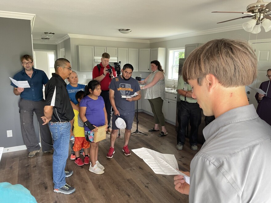 Members of the Mennonite and Amish communities sing hymns to Francisco Rios' family (center) in their new home.