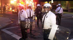 Cincinnati Police in riot gear stand gaurd as firefighters put out a fire started in Over-the-Rhine, Tuesday, April 10, 2001, following protests over the fatal police shooting of an unarmed black man turned violent.