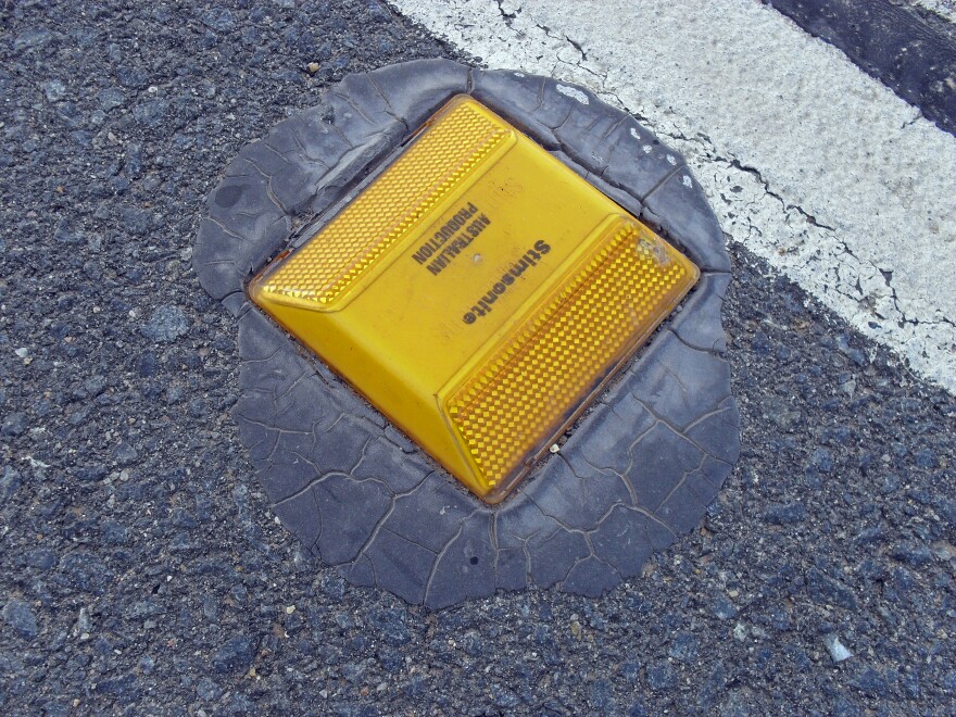 A raised pavement marker. The marker is yellow and says, "Stimsonite, Australian Production."