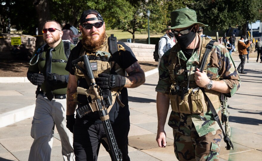 Kris Hunter (center) and two other armed protesters join a small rally outside of the state Capitol grounds on Sunday.