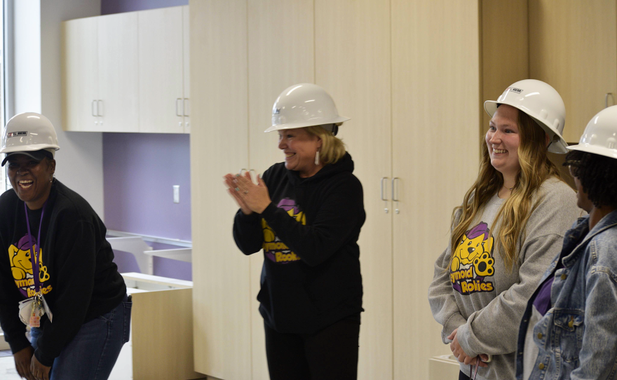 Women in hardhats clap and laugh in celebration.