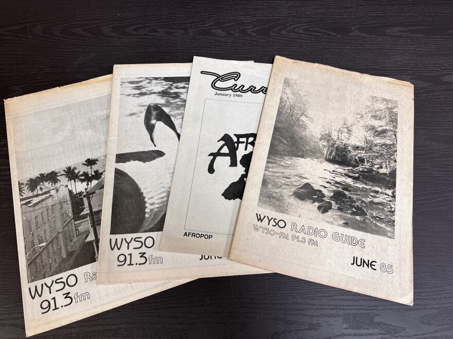Newsprint program guides from the WYSO archives are fanned out on a table.