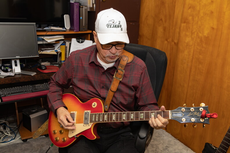 Damian Rodriquez plays guitar in his home office, Paul, ID. Photo by Arlie Sommer, October 28, 2022.