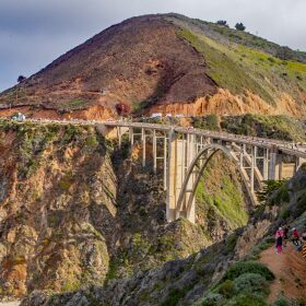 Highway 1 on the Big Sur cliffs during the 2022 Big Sur Marathon. Runners snake along one side of the highway.