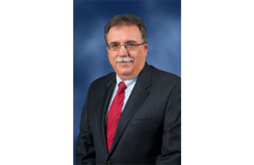 Headshot of Mark Owens, chair of the Montgomery Democratic Party. He is wearing a black suit with a red tie.