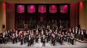 A Kalamazoo Concert Band group photo on stage at Miller Auditorium with holiday decorations