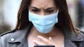 A woman wearing a mask looks at smartphone