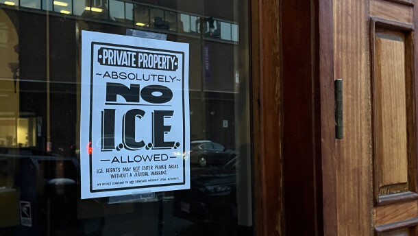 A sign meant to deter federal immigration enforcement agents hangs in the window of a business on Congress Street in Portland.