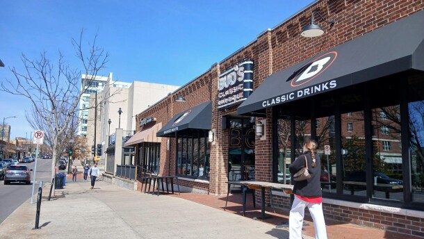 A few students and pedestrians walk on the sidewalks outside Campus Bar & Grill and Bud's Classic BBQ on 9th Street. 