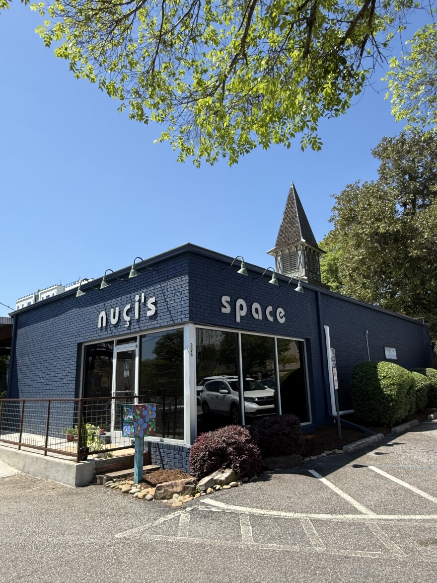 The exterior of Nuçi’s Space, a dark blue brick building in downtown Athens, is shown on a sunny day.