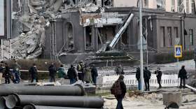 People gather at the bottom of a hotel, which has been partially destroyed by a Russian strike in the center of the Ukrainian capital Kyiv on Saturday.