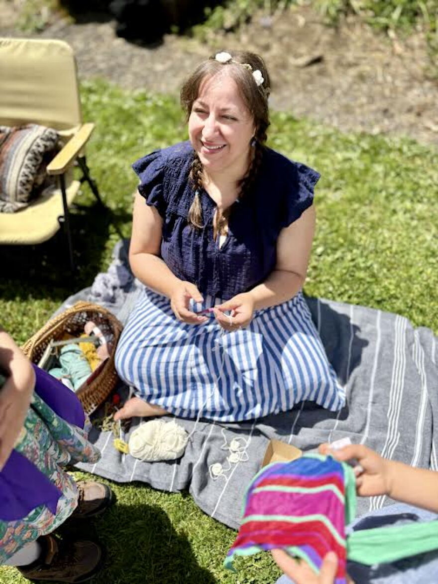 Women sitting on a blanket surrounded by sewing projects