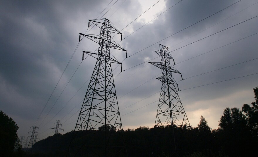 Power transmission lines shown against a sky of gathering storm clouds