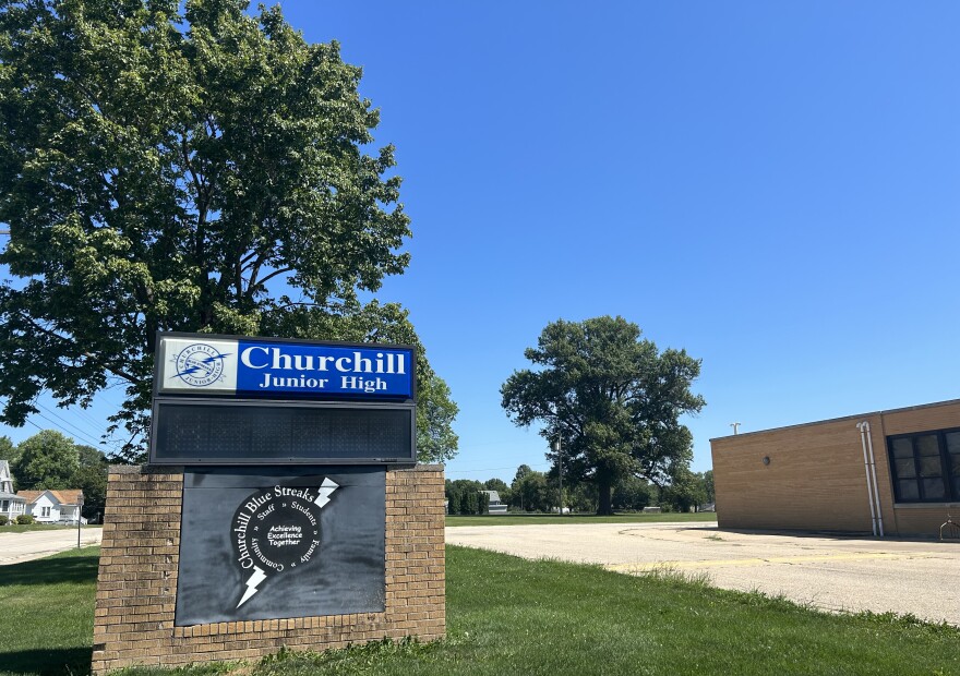  The sign outside the former Churchill Junior High School building in Galesburg, with tall oak trees behind it. 
