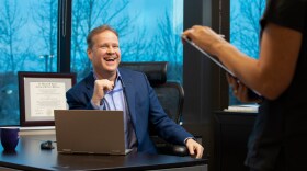 man sitting at desk in medical office laughing