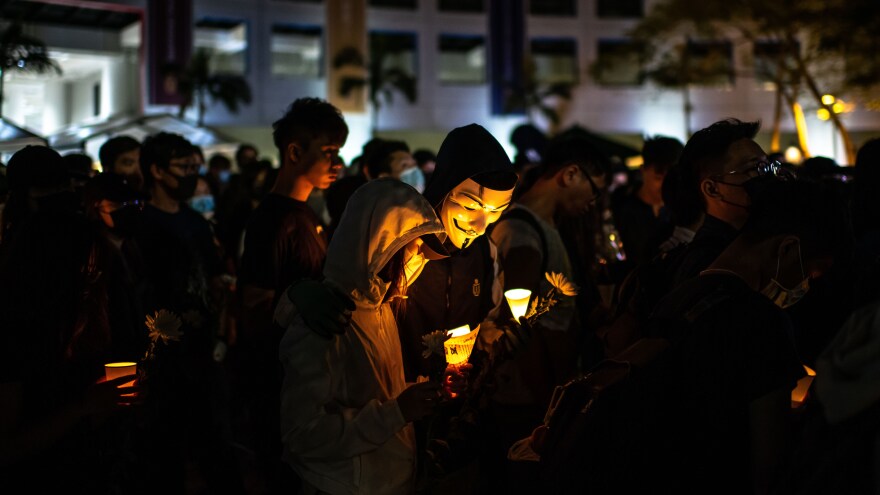 Masked demonstrators attend a candlelight vigil to pay tribute to Chow Tsz-lok, a university student who fell during protests Monday and died early Friday morning.