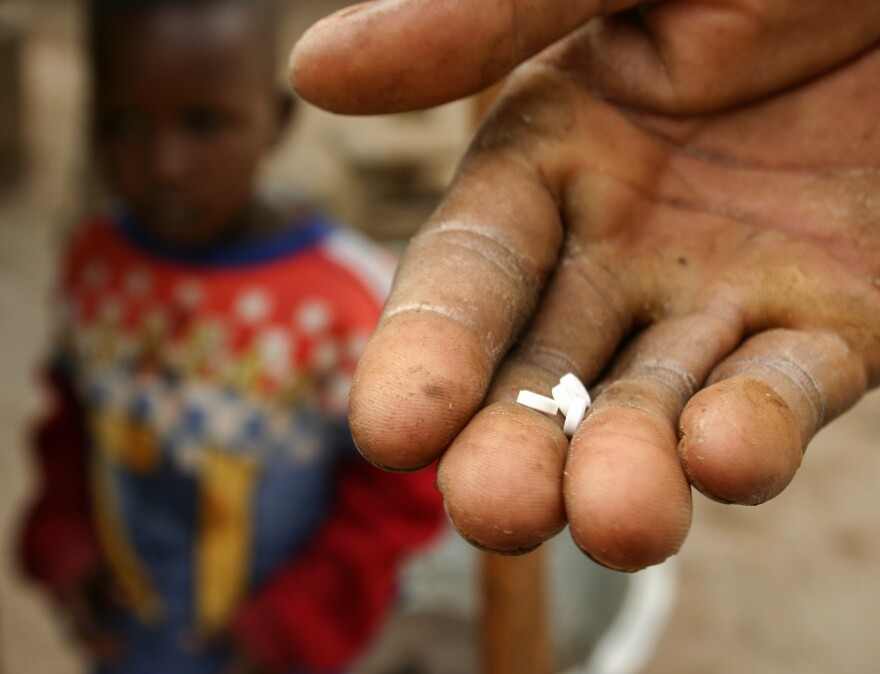 A volunteer shows the four ivermectin tablets he's about to give a woman for her yearly dose.